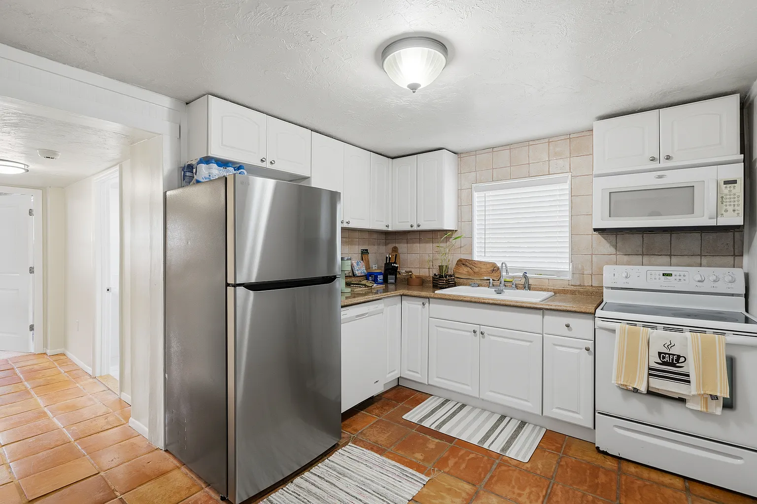 Kitchen with white cabinetry and terracotta floor